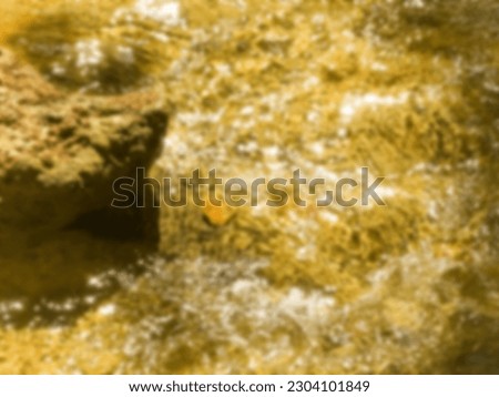 Waterfall flowing on rocks resembling golden color, in blur mode 
