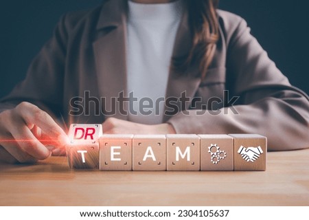 Businesswoman turns wooden cubes and changes the word "DREAM" to "TEAM". Dream team symbol, business and dream team  concept.