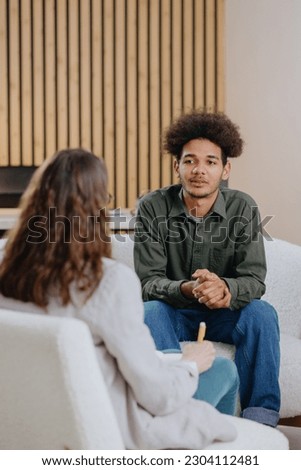 young man in consultation with psychologist is taking care of mental health. Psychotherapy for treatment of disorders and depression, insomnia. African American guy tells doctor about his problems Royalty-Free Stock Photo #2304112481
