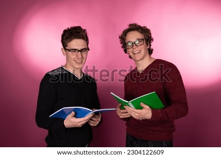 Two young attractive students are posing in the studio. Happy men.