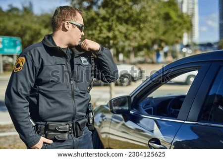 Police, radio and security with a man officer outdoor on patrol while talking to headquarters for a situation report. Law, safety and communication with a policeman on the street for justice Royalty-Free Stock Photo #2304125625