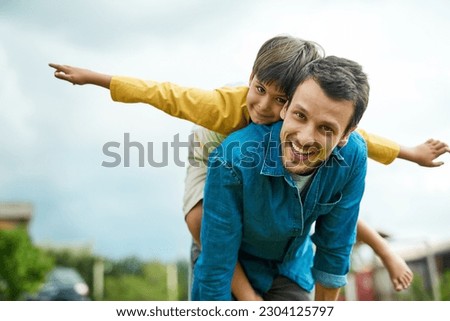 Portrait, children and a son on back of his dad outdoor in the garden to fly like an airplane while bonding together. Family, kids and a father carrying his boy child while playing a game in the yard Royalty-Free Stock Photo #2304125797