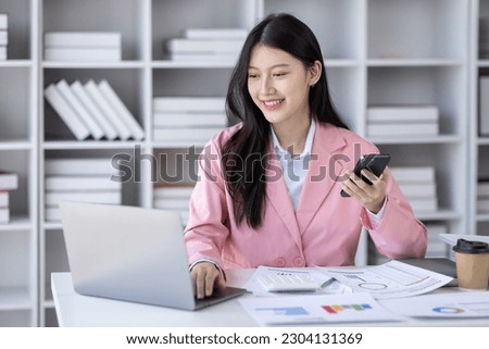 Young Asian professional business woman office worker analyst sitting at desk call phone laptop thinking on project plan, analyzing marketing or financial data online, watching elearning webinar.	