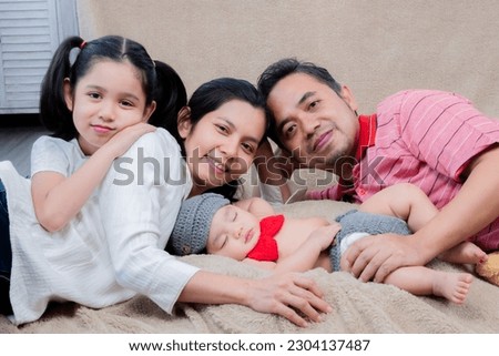 Happy Asian family taking pictures together. Parents, eldest daughter and youngest son Spend time together on a family day. Mother, father and adorable children smile and look at the camera.