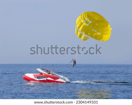 A yellow parasail wing pulled by a powerboat. Guy takes a selfie Royalty-Free Stock Photo #2304149331