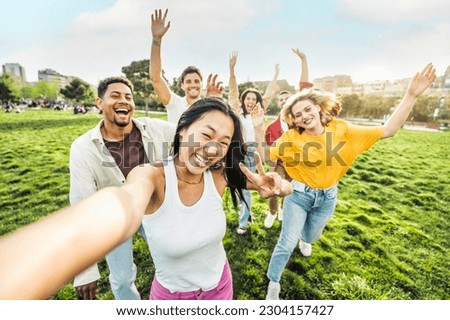 Multiracial group of friends taking selfie picture with smart mobile phone outside - Millenial people enjoying summer day at the park - Life style concept with guys and girls hanging outdoors  Royalty-Free Stock Photo #2304157427