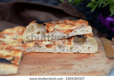 Bread texture of home baked pizza, sourdough bread cut in half. Pizza, traditional Italian wheat bread with open crumb texture. Sliced flat bread stuffed with tomato, cheese and smoked ham on wood. Royalty-Free Stock Photo #2304184327