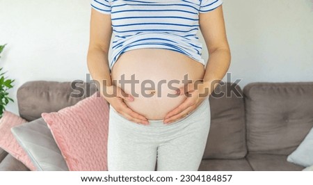 Pregnant woman hugs her belly. Selective focus. Cute.