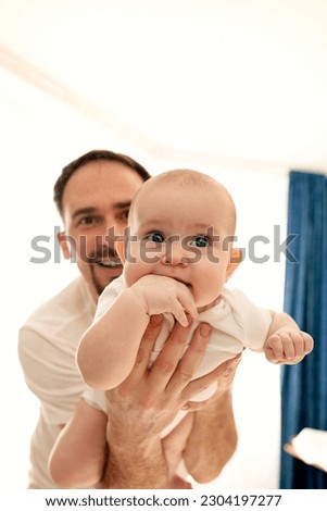Close-up of a young happy dad holding his baby in his arms. The father hugs the child. Baby is happy in his father's arms. Royalty-Free Stock Photo #2304197277