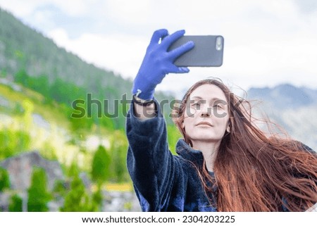 Happy woman with long hair takes a selfie on the background of mountains and multinsky lake