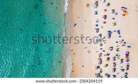 Aerial top view Of people crowd relaxing on beach with colorful umbrellas in Phuket, Thailand, Aerial view of sandy beach with tourists swimming in beautiful clear sea water in Thailand. Royalty-Free Stock Photo #2304204119