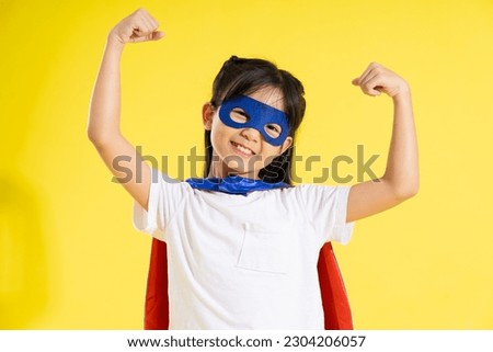 Portrait of little girl dressed up as a hero, isolated on yellow