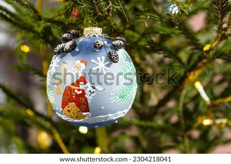 painted glass ball with santa claus image on christmas tree close up indoor