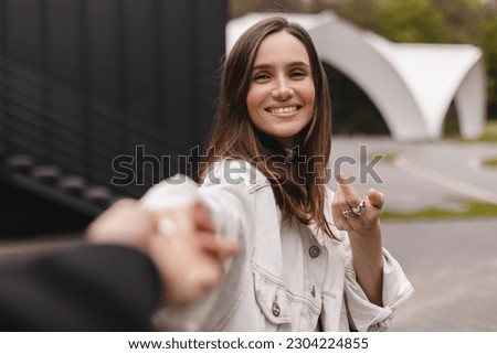 Follow me. Boyfriend following girlfriend holding hands, walking in city, copy space. Come with me. happy young woman pulling guy's hand, hand in hand, concept of carefree modern life. Royalty-Free Stock Photo #2304224855