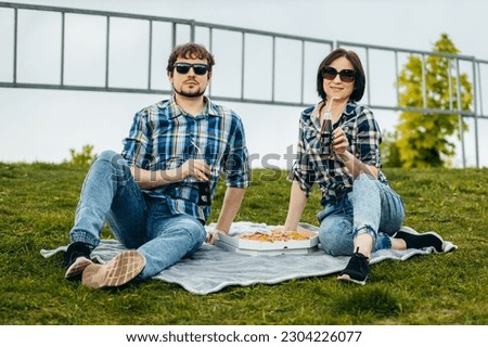 Young stylish family eating pizza snack outdoor