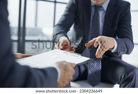 Two businessmen are sitting on chairs in the office while closing a deal. Royalty-Free Stock Photo #2304236649