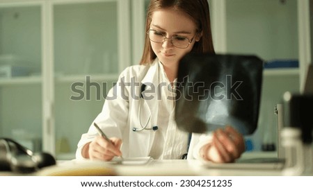 Doctor pulmonologist examining x-ray lungs and writing patient medical history in clinic