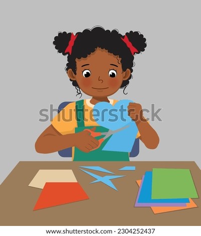 Cute little African girl cutting colored paper with scissors making heart shape paper cut art craft