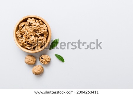 Walnut kernel halves, in a wooden bowl. Close-up, from above on colored background. Healthy eating Walnut concept. Super foods with copy space. Royalty-Free Stock Photo #2304263411