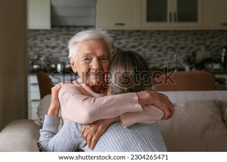 Grandmother and granddaughter hugging in the living room. Two adult women of different age. Family values concept. Close up, copy space, background. Royalty-Free Stock Photo #2304265471