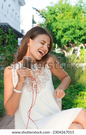 Happy smiling young pretty woman is listening to music in headphone and having fun.