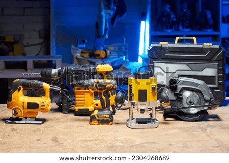 A set of tools and electrical devices is on the table. circular saw, screwdriver, perforator, drill, jigsaw, router in a carpentry workshop Royalty-Free Stock Photo #2304268689