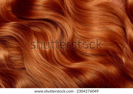 Red hair close-up as a background. Women's long orange hair. Beautifully styled wavy shiny curls. Hair coloring bright shades. Hairdressing procedures, extension. Royalty-Free Stock Photo #2304276049