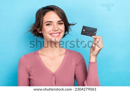 Photo of good mood cute woman dressed pink shirt showing credit card smiling isolated blue color background