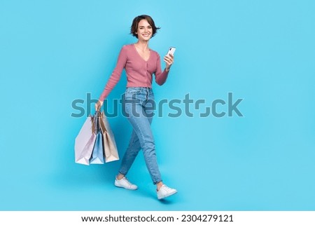 Full length size photo of young walking girl blogging order eshopping hold bargains promo new clothes isolated on blue color background