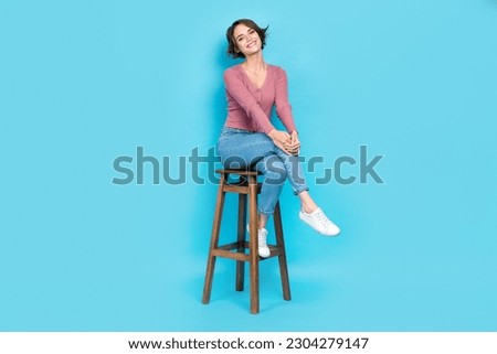 Full size photo of nice cute good mood woman wear pink cardigan sitting on chair hold hands on knee isolated on teal color background