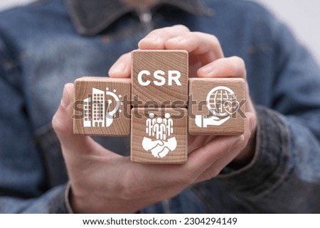 Man holding wooden cubes with icons and acronym: CSR. Concept of CSR Corporate Social Responsibility. Business and organization concept of corporate social responsibility and giving back to community. Royalty-Free Stock Photo #2304294149