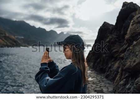 Young tourist taking photos of the landscape with her mobile phone
