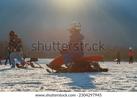 child comes down from the mountain riding a red sled