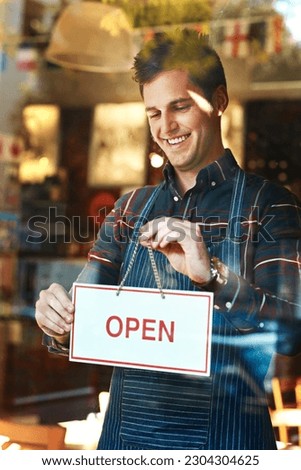 Open sign, smile and man with business, startup success and service with restaurant, window and coffee shop. Male person, employee and entrepreneur with billboard, poster and opening retail store