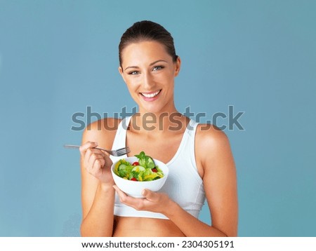 Woman in portrait, smile and eating salad, diet and healthy food with weight loss isolated on blue background. Health, wellness and nutrition with vegetables, female model in studio and mockup space