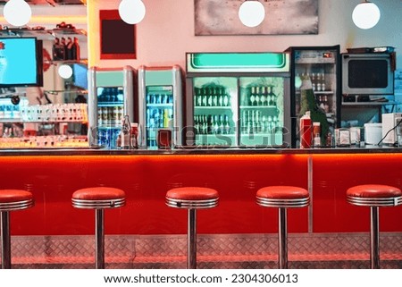 Retro, vintage and stools with interior in a diner, restaurant or cafeteria with funky decor. Trendy, old school and chairs by a counter or bar in groovy, vibrant and stylish old fashioned empty cafe Royalty-Free Stock Photo #2304306013