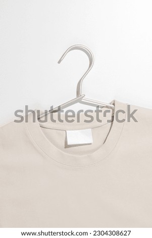 Beige t-shirt with blank label on a clothes rack. Ecology concept. Mockup.