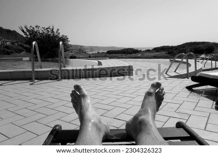 Man laying in front of swimming pool in black and white. Seasonal background and natural pattern.