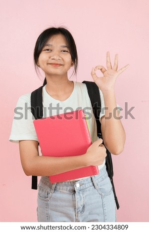 Happy student young girl hold pink book and backpack on pink background.