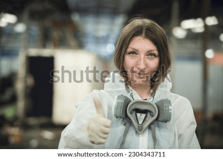 Female scientist in chemical protective clothing showing thumbs up while standing in a chemical leaks in an industrial site and a restricted area.