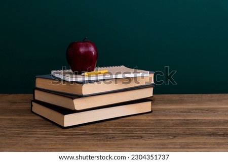 Red apple on book in front of the blackboard