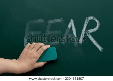 Erasing the word fear on chalkboard Royalty-Free Stock Photo #2304351807