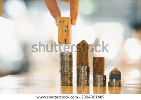 Wood house and row of coin money on wood table and , selective focus, Planning to buy property. Choose what's the best. A symbol for construction ,ecology, loan concepts.	
