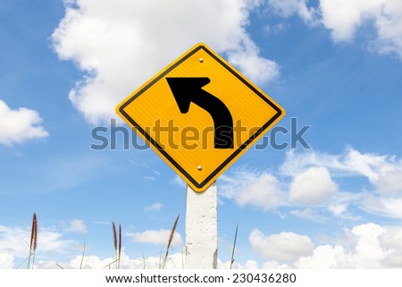 Left turn warning sign in farmland with cloudy blue sky background, Korat provinve, Thailand.