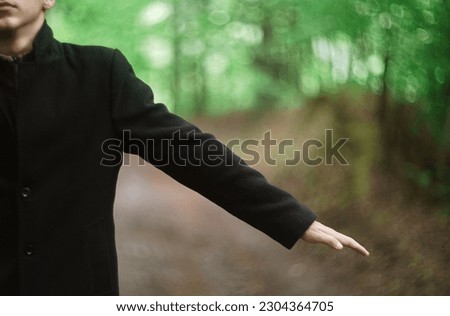 concept photo of a young man in a black coat and cylinder hat posing outdoor