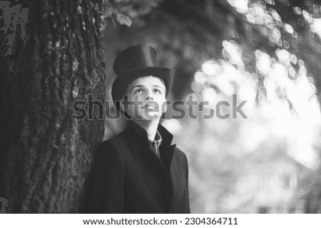 concept photo of a young man in a black coat and cylinder hat posing outdoor
