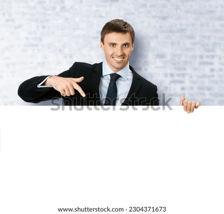 Image of business man professional bank manager confident black suit. Businessman stand behind, hang over, show point finger empty white banner signboard. White bricks office background.