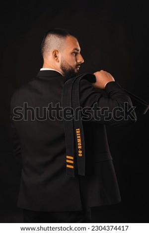 Vertical shot of a young strong man holding his Taekwon-Do black belt. Royalty-Free Stock Photo #2304374417