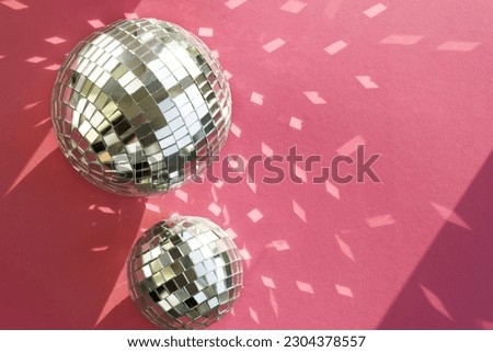 Disco ball on a pink background with shadows and highlights of bright sunlight. Abstract holiday background