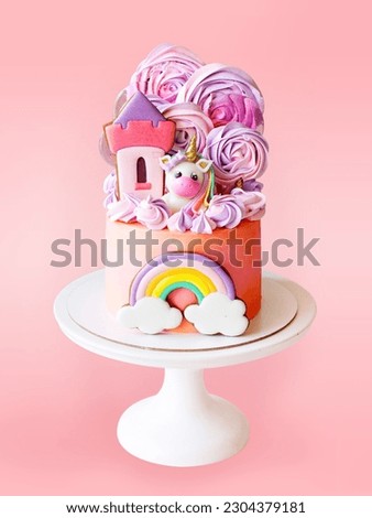 Cute pink birthday cake for a little girl with fondant unicorn, with gingerbread cookies isolated on pink background, vertical orientation